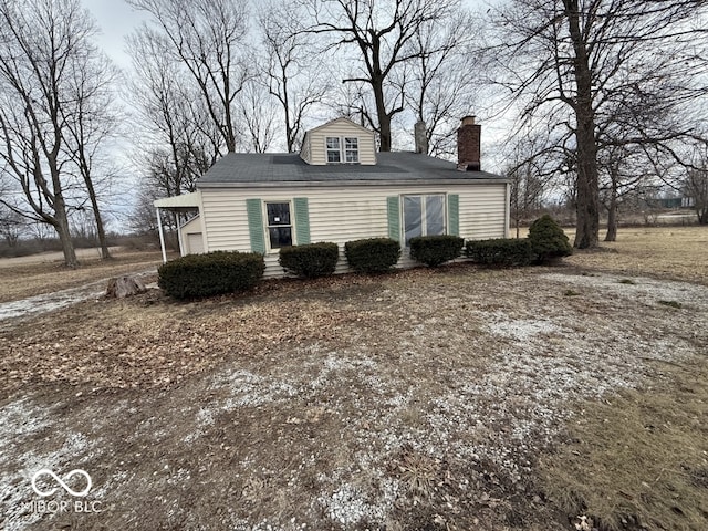 view of front facade with dirt driveway and a chimney