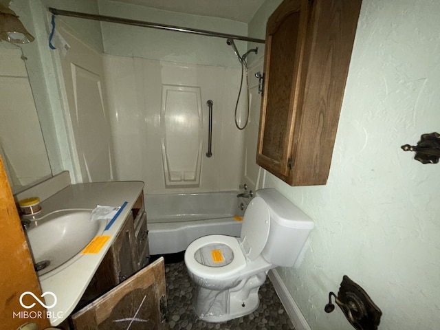 bathroom with a textured wall, toilet, vanity, and shower / tub combination