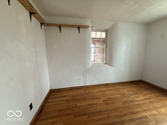 spare room with baseboards, wood finished floors, and a textured wall