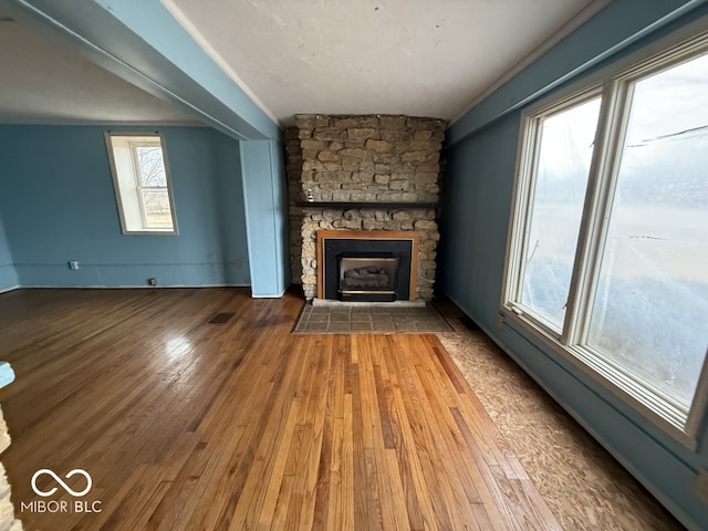 unfurnished living room with visible vents, hardwood / wood-style flooring, a fireplace, baseboards, and baseboard heating