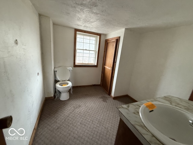 bathroom with vanity, toilet, baseboards, and a textured ceiling