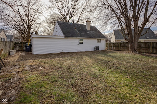 rear view of house featuring central air condition unit, a yard, and a fenced backyard