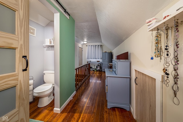 interior space featuring dark wood-style floors, baseboards, lofted ceiling, a textured ceiling, and a barn door