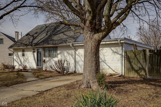 view of front facade featuring fence and a shingled roof