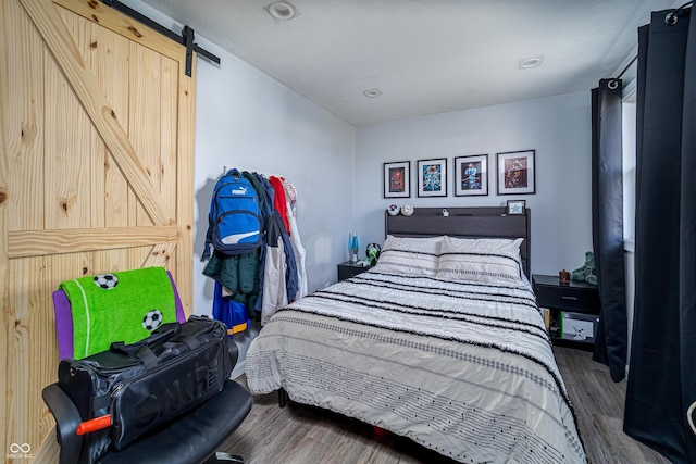 bedroom with a barn door and wood finished floors