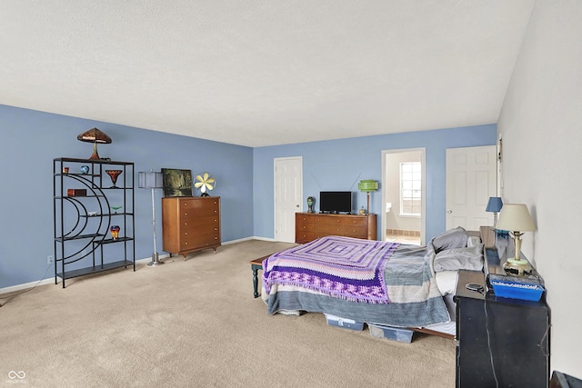 bedroom with ensuite bathroom, baseboards, and carpet floors