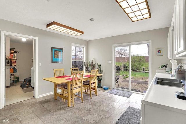 dining room with baseboards, stone finish floor, and plenty of natural light