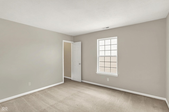 spare room featuring visible vents, baseboards, a wealth of natural light, and light carpet