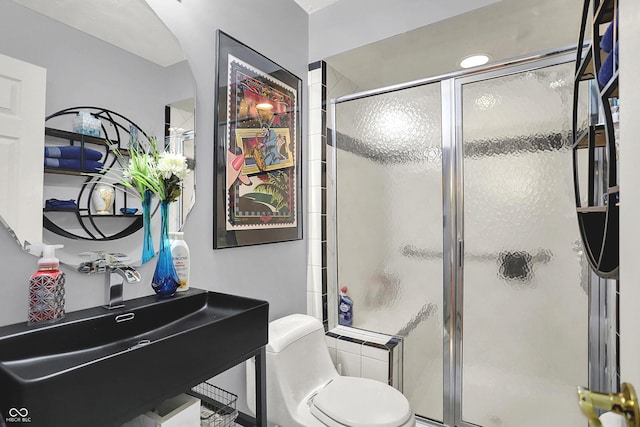 bathroom with a sink, toilet, and a stall shower