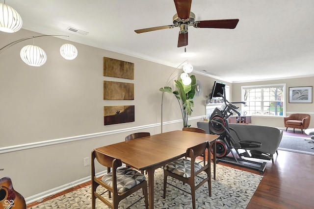 dining area with ornamental molding, a ceiling fan, visible vents, wood finished floors, and baseboards