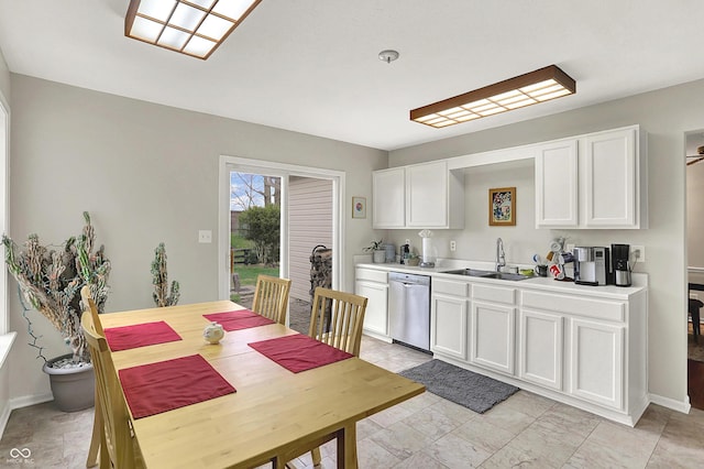 kitchen with baseboards, light countertops, white cabinetry, stainless steel dishwasher, and a sink