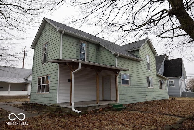 back of property featuring a porch and a shingled roof