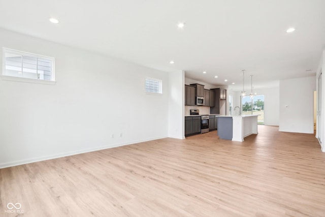 unfurnished living room featuring recessed lighting, light wood-type flooring, a healthy amount of sunlight, and a sink