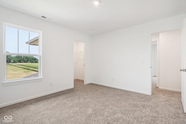 carpeted spare room with a wealth of natural light, visible vents, and baseboards