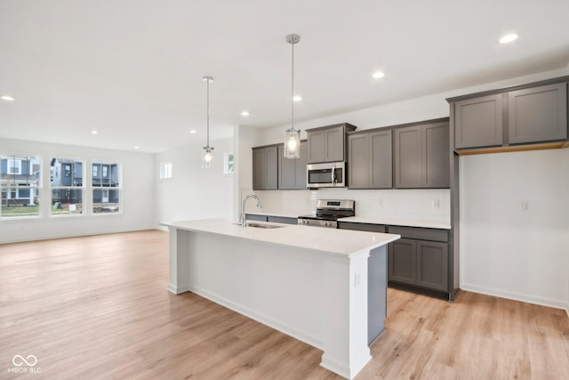 kitchen with a sink, stainless steel appliances, light wood-type flooring, and decorative backsplash