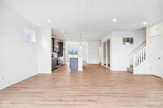 unfurnished living room featuring recessed lighting, stairs, and light wood finished floors