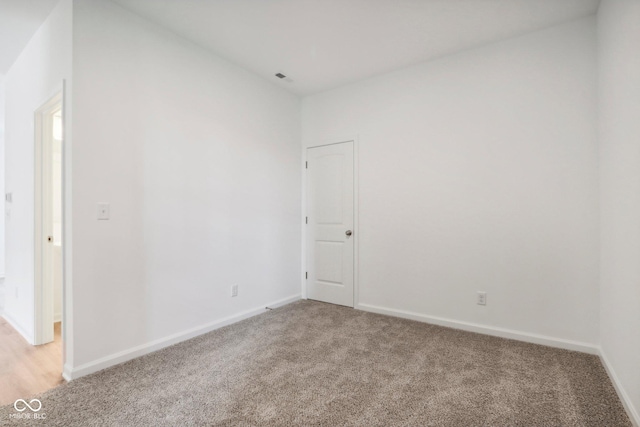 empty room featuring visible vents, baseboards, and light colored carpet