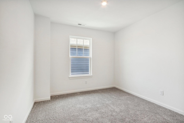 carpeted spare room featuring baseboards and visible vents