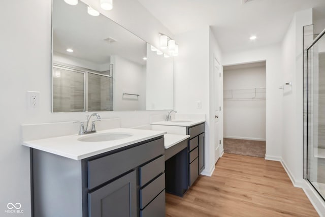 full bathroom featuring a sink, wood finished floors, two vanities, and a stall shower