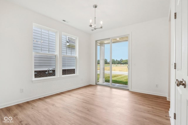 empty room with visible vents, an inviting chandelier, baseboards, and light wood-style floors