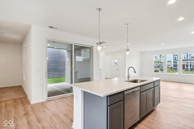 kitchen with light wood finished floors, gray cabinetry, light countertops, stainless steel dishwasher, and a sink