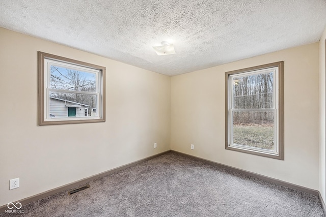 carpeted spare room with visible vents, a textured ceiling, and baseboards