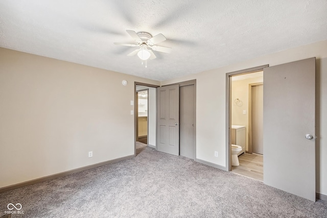 unfurnished bedroom featuring baseboards, light colored carpet, ensuite bath, a closet, and a textured ceiling