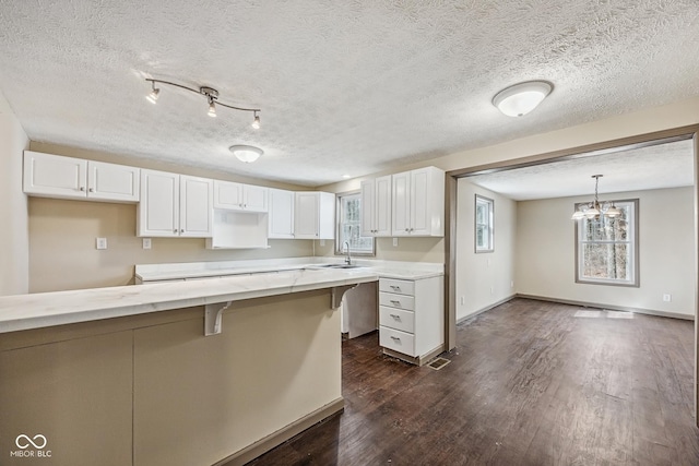 kitchen with dark wood-style floors, white cabinets, a wealth of natural light, and a sink