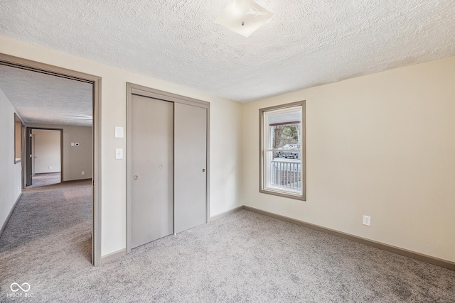 unfurnished bedroom with a closet, baseboards, a textured ceiling, and carpet flooring