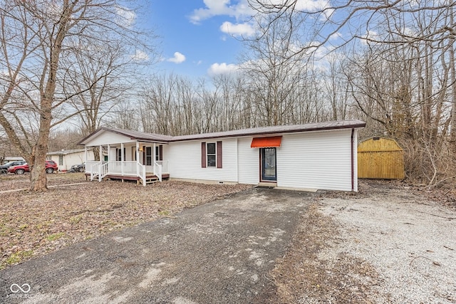 view of front of home with a porch, metal roof, aphalt driveway, and crawl space