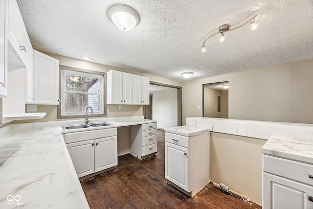 kitchen featuring a sink, a textured ceiling, dark wood-style flooring, and white cabinetry