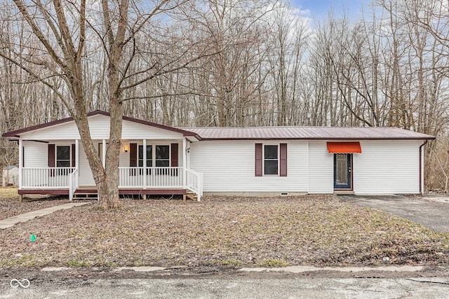 view of front of home featuring crawl space, metal roof, covered porch, and driveway