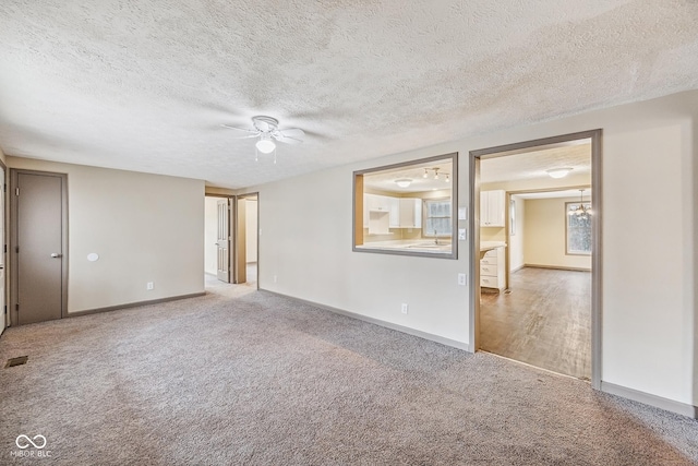 empty room with a sink, baseboards, carpet floors, and a ceiling fan