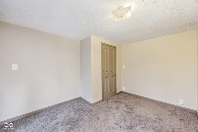 carpeted empty room with a textured ceiling and baseboards