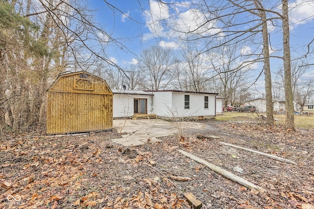 rear view of property with entry steps, a storage shed, an outdoor structure, and a patio