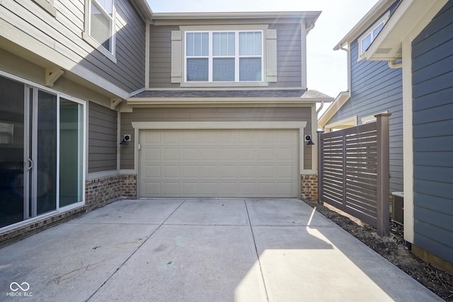 garage featuring driveway and fence