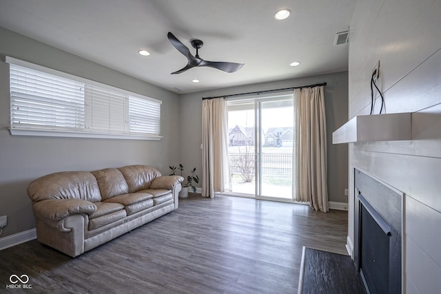 living room with visible vents, a fireplace, baseboards, ceiling fan, and dark wood-style flooring