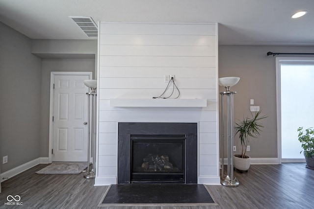 interior details with visible vents, a fireplace with flush hearth, baseboards, and wood finished floors