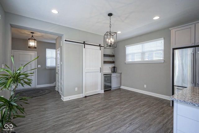 kitchen with a wealth of natural light, dark wood-type flooring, high end fridge, a barn door, and wine cooler