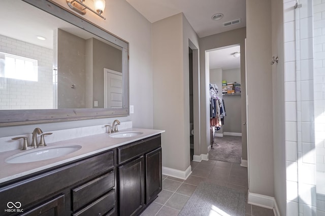 bathroom featuring a sink, visible vents, double vanity, and tile patterned flooring