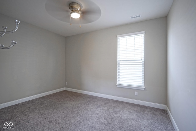 carpeted spare room featuring baseboards, visible vents, a wealth of natural light, and ceiling fan