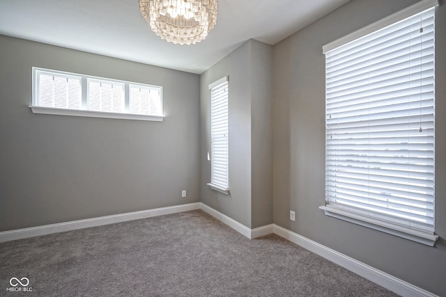 spare room featuring a notable chandelier, baseboards, and carpet floors