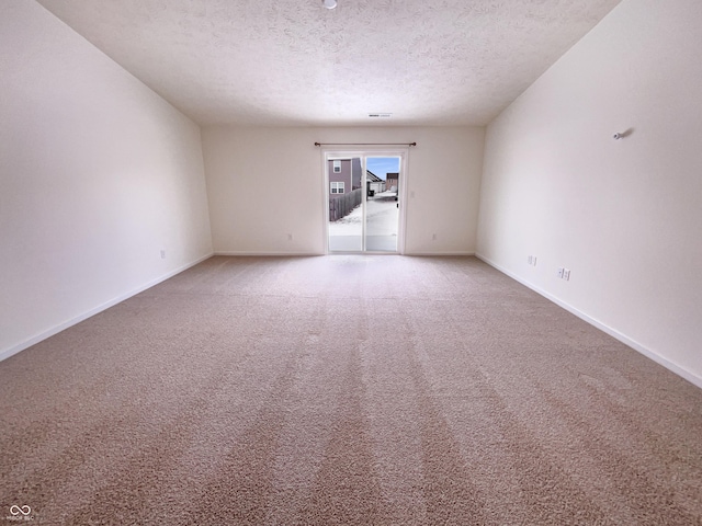 unfurnished room with visible vents, light colored carpet, baseboards, and a textured ceiling