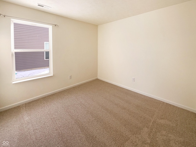 carpeted empty room featuring visible vents and baseboards