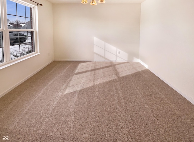 spare room with baseboards and carpet floors