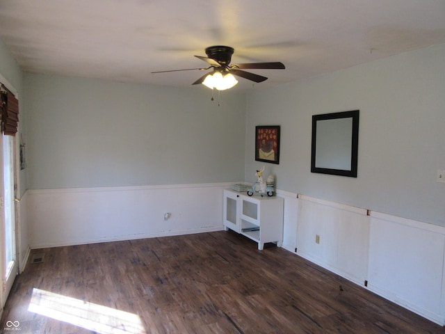 unfurnished room featuring a wainscoted wall, ceiling fan, and wood finished floors