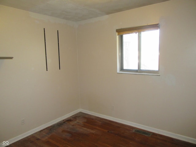 unfurnished room with dark wood finished floors, baseboards, and visible vents