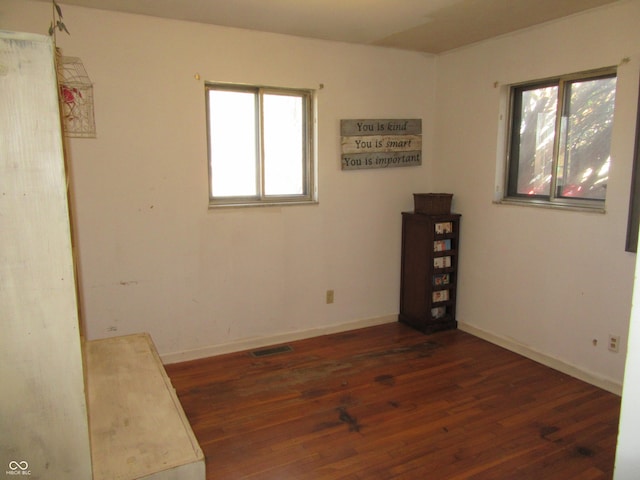 spare room featuring wood finished floors, visible vents, and baseboards