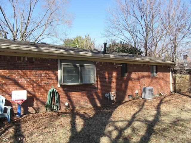 view of home's exterior featuring crawl space, brick siding, central AC, and fence