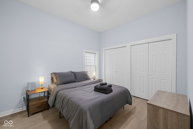 bedroom featuring light wood finished floors, baseboards, and two closets